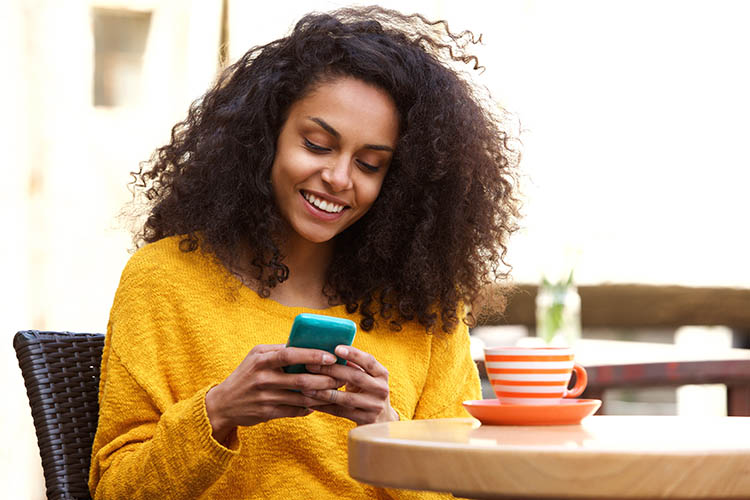 Close,Up,Portrait,Of,Beautiful,Young,African,American,Woman,Reading Close up portrait of beautiful young african american woman reading text message on mobile phone at coffee shop